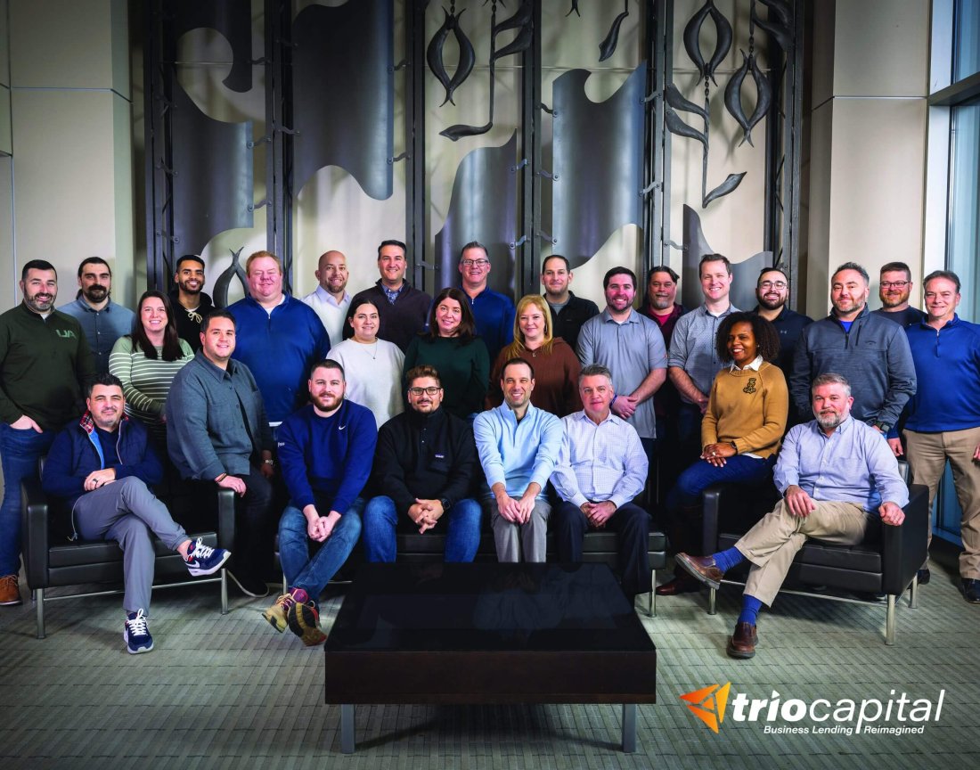 A group of people in a large meeting room, posed and smiling at the camera